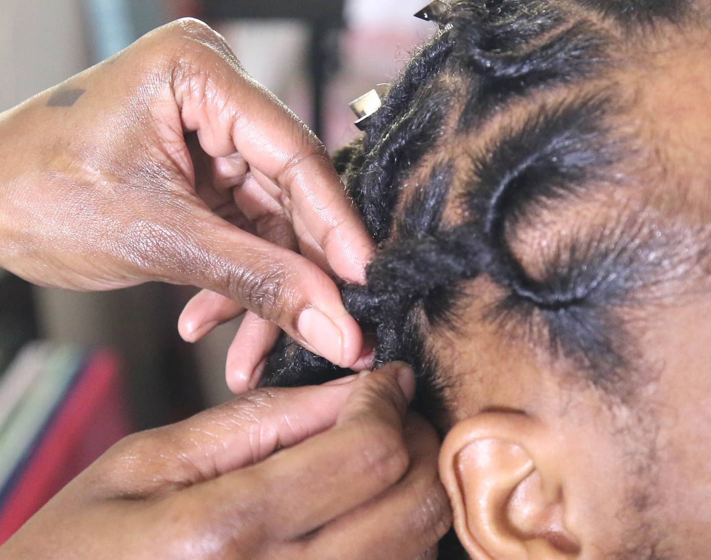 Hairstylist Mariyah Ofei braids the locks of DeKalb resident Michael Calhoun Thursday, Feb. 24, 2022, in her home studio in DeKalb.  Ofei, who plays sports herself, specializes in working with others who also have locks.