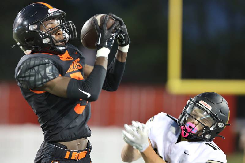 DeKalb's LaBrian Carrington comes up with an interception in front of Sycamore's Burke Gautcher but it was called back due to a roughing the passer penalty during the First National Challenge Friday, Aug. 26, 2022, in Huskie Stadium at Northern Illinois University in DeKalb.