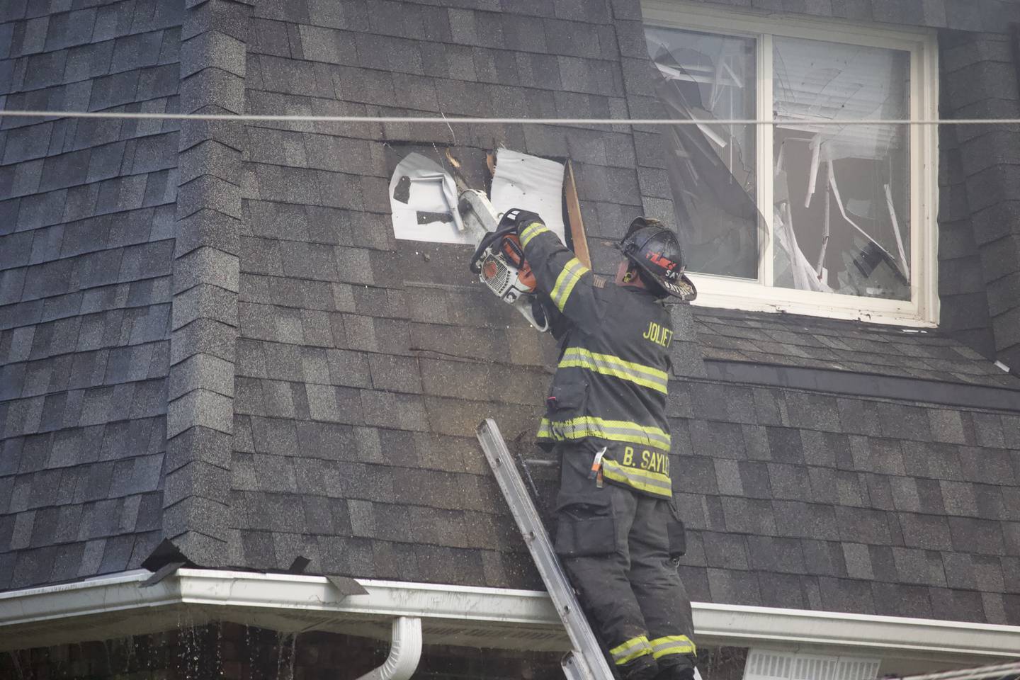 A Joliet firefighter using a chainsaw as part of an effort to put out an apartment fire on Tuesday, June 10, 2025, near Essington Road in Joliet.
