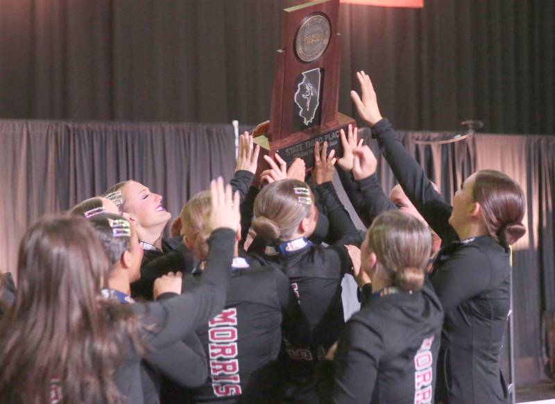 Members of the Morris dance team hoist the Class 1A  IHSA State Dance third-place trophy on Saturday, Feb. 1, 2025 at Grossingers Motor Arena in Bloomington.