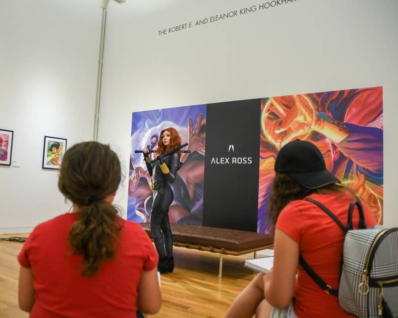 Mia Gallegos, 7 years old, and sister Leah Gallegos,11 years old, of Chicago sketch on paper The Black Widow who is portray by Lisa J. during a live model demonstration on Saturday June 24, 2023, during The Marvelcity: The Art of Alex Ross exhibit held at the Elmhurst Museum.