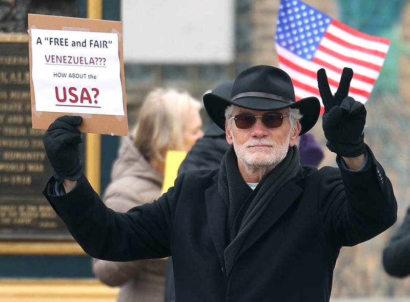 Roger Hintzsche, of DeKalb, gives the peace sign Tuesday, Jan. 6, 2026, during a Venezuela Rapid Response Rally at Memorial Park on the corner of First Street and Lincoln Highway in DeKalb. The protesters gathered to voice their opposition to President Donald Trump and the administrations recent actions in Venezuela.