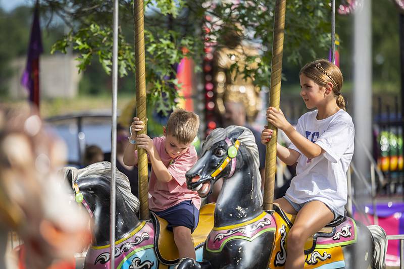 Corbin Burke (left), 5, and Brynn Simonton, 10, ride the Merry-Go-Round Wednesday, July 3, 2024 at the Petunia Fest carnival.
