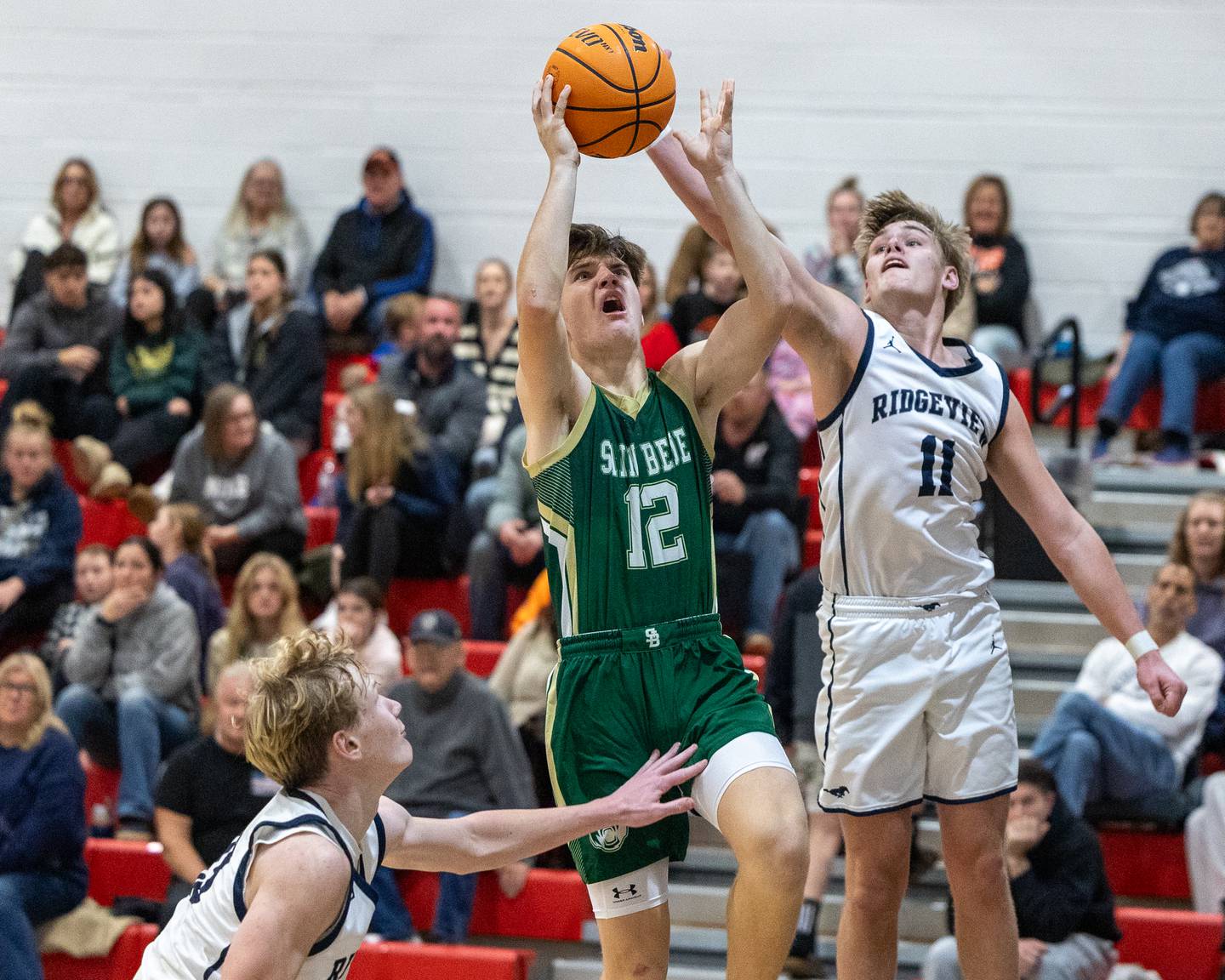 St. Bede's Carson Riva (12) lays the ball up as Cole Kennedy (11) of Ridgeview attempts to deflect on Wednesday, Nov. 26, 2025, at Woodland School in rural Streator.