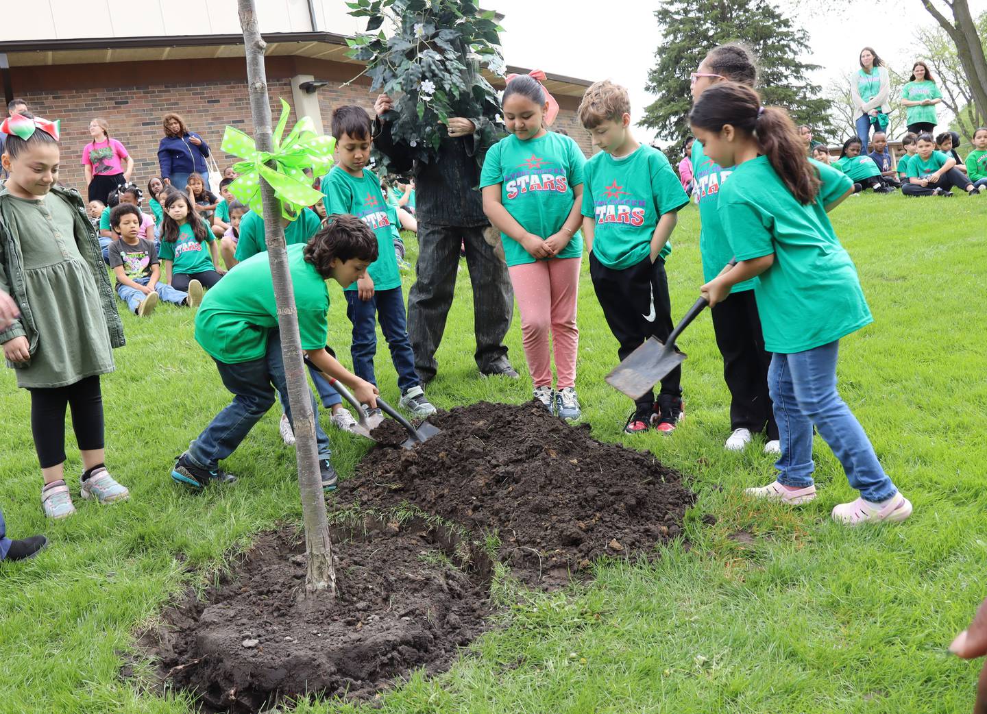 Lynne Thigpen Elementary School second-grade students Adrian Palmerin, Fernando Chacin Castellano, Romina Mendez, Jaxtyn Thompson, Symora Michalek, and Ariyah Lloyd help plant a new tree at their school on Friday, April 24, 2026.