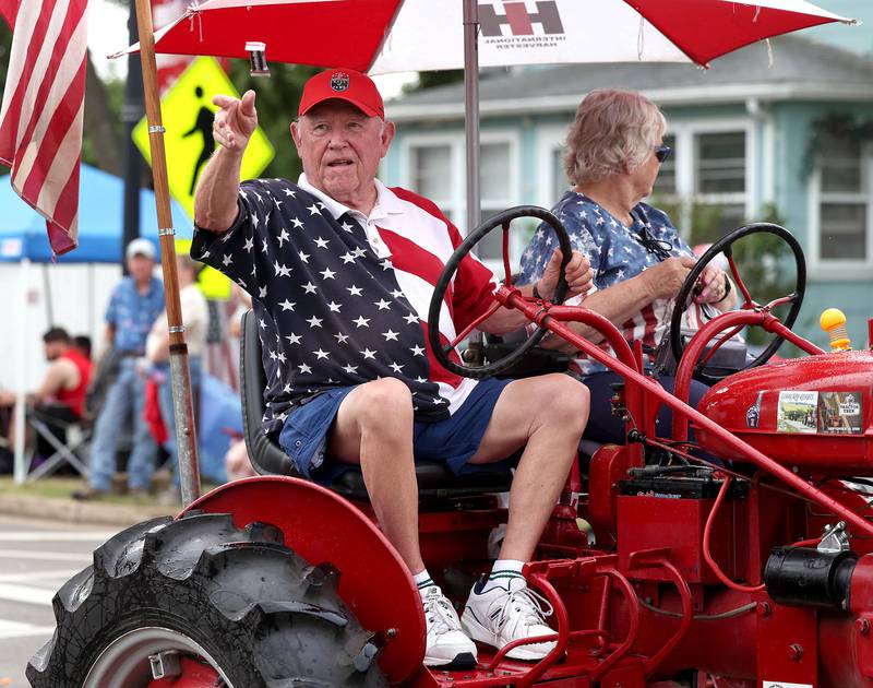A vintage tractor driver throws candy as they make their way down Main Street Friday, July 4, 2025, during the Fourth of July parade in downtown Kirkland.