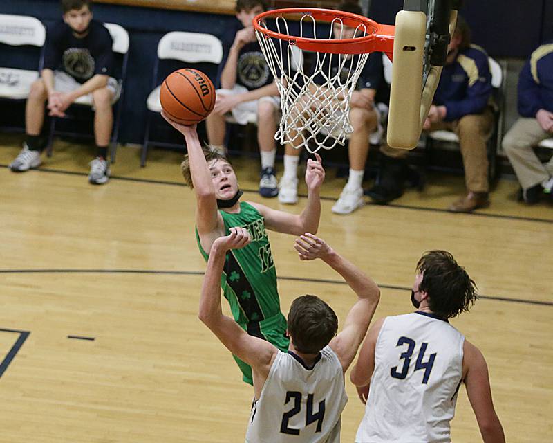 Seneca's Braden Ellis (12) lofts a one-handed shot over Marquette's Caden Eller (24) and Brady Ewers (34) in Friday's Tri-County showdown at Bader Gym in Ottawa.