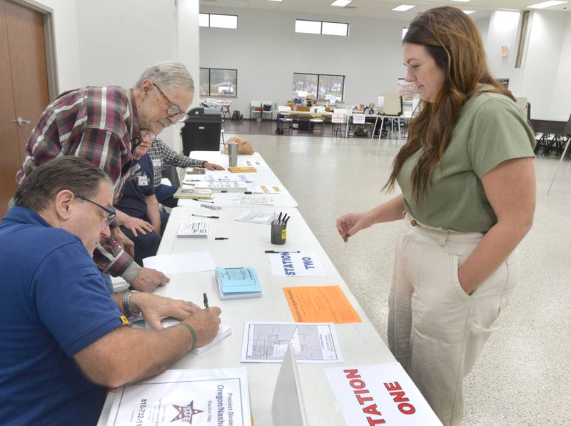 Alyssa Barrinson of Oregon waits for her ballot from election judges at her precinct sign-in table before voting at the Rock River Center in Oregon on Tuesday, Nov. 5, 2024.