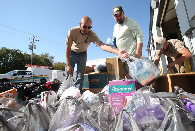Elemore Electric employees (from left) Sky Abrassart Nolan Drake and Dan Elmore, grab donated supplies before leaving for North Carolina on Friday, Oct. 4, 2024 at their shop in Dover. The crews are taking two trucks and two trailers full of equipment and supplies to Hendersonville and Spruce Pine N.C. to assist in the Hurricane Helene relief efforts.