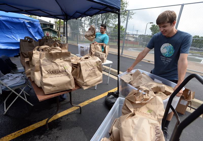 LeaderShop volunteers (left) David Banda of Chicago and Jude Short of La Grange provide hygiene products to students attending District 105 Back to School/Neighborhood Fest held at Ideal Park Saturday Aug 20, 2022.