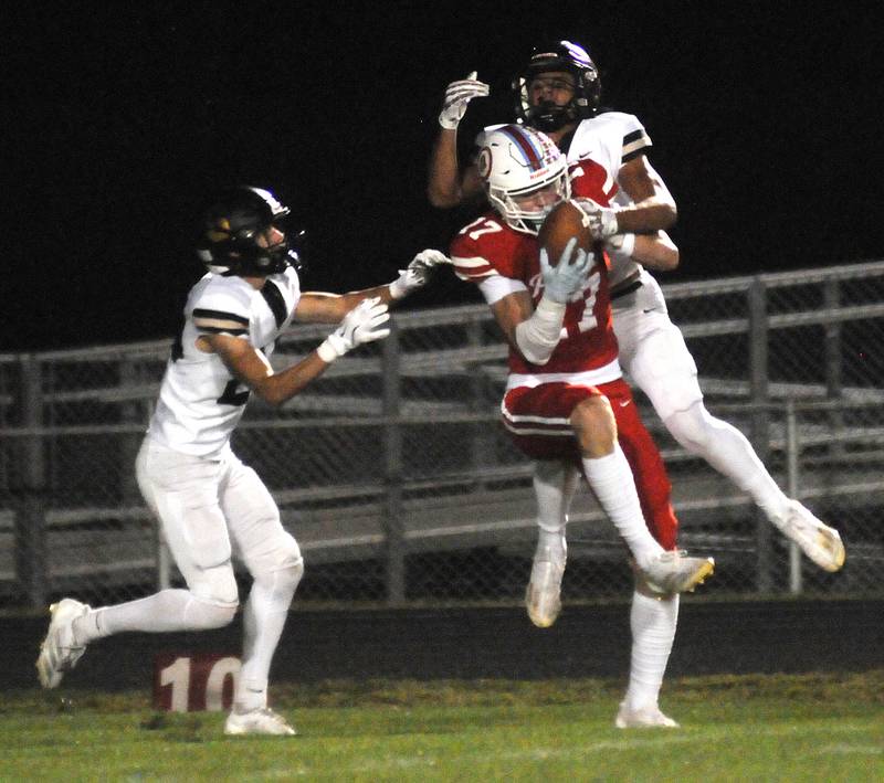Ottawa senior Owen Sanders (17) secures a long pass as Sycamore's Crewe Bartlett (left) and Josiah Mitchell defend on Friday, Sept. 26, 2025 at King Field.