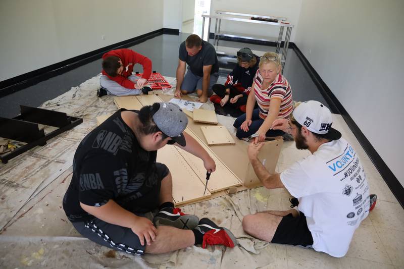 Clients and instructors at McHenry High School District 156 put together shelving for Across the Bridge, 1774 N. Richmond Road, McHenry, on Monday, Sept. 25, 2023. The storefront will give the clients practice in selling in a retail store environment.