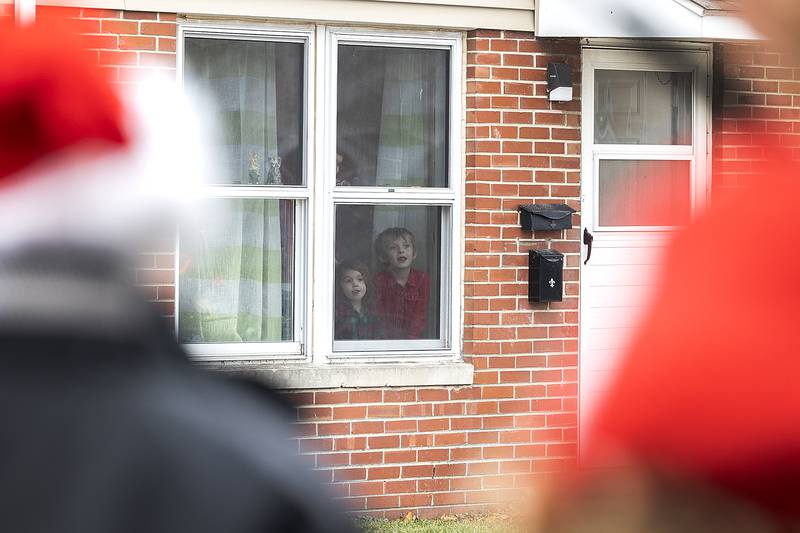 Kids watch out the window as Santa and friends unload gifts from the sleigh Monday, Dec. 23, 2024, in Rock Falls.