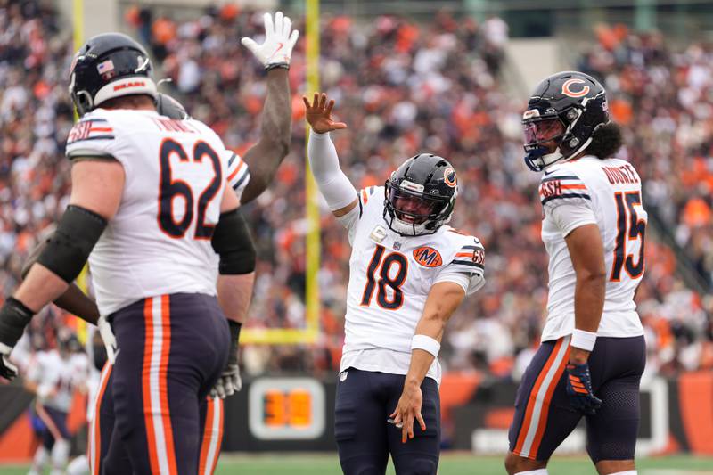 Chicago Bears quarterback Caleb Williams (18), center, celebrates a touchdown pass with Chicago Bears wide receiver Olamide Zaccheaus (14) during an NFL football game against the Cincinnati Bengals, Sunday, Nov. 2, 2025, in Cincinnati. (AP Photo/Kareem Elgazzar)