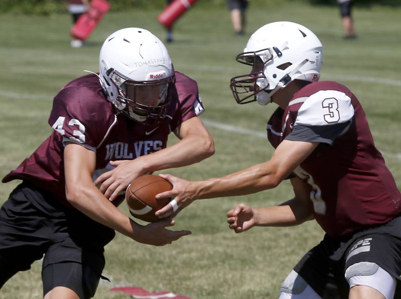 Prairie Ridge’s Tyler Vasey, right, hands the ball off to Drake Tomasiewicz during summer football practice Tuesday, July 12 2022, at Prairie Ridge High School in Crystal Lake.