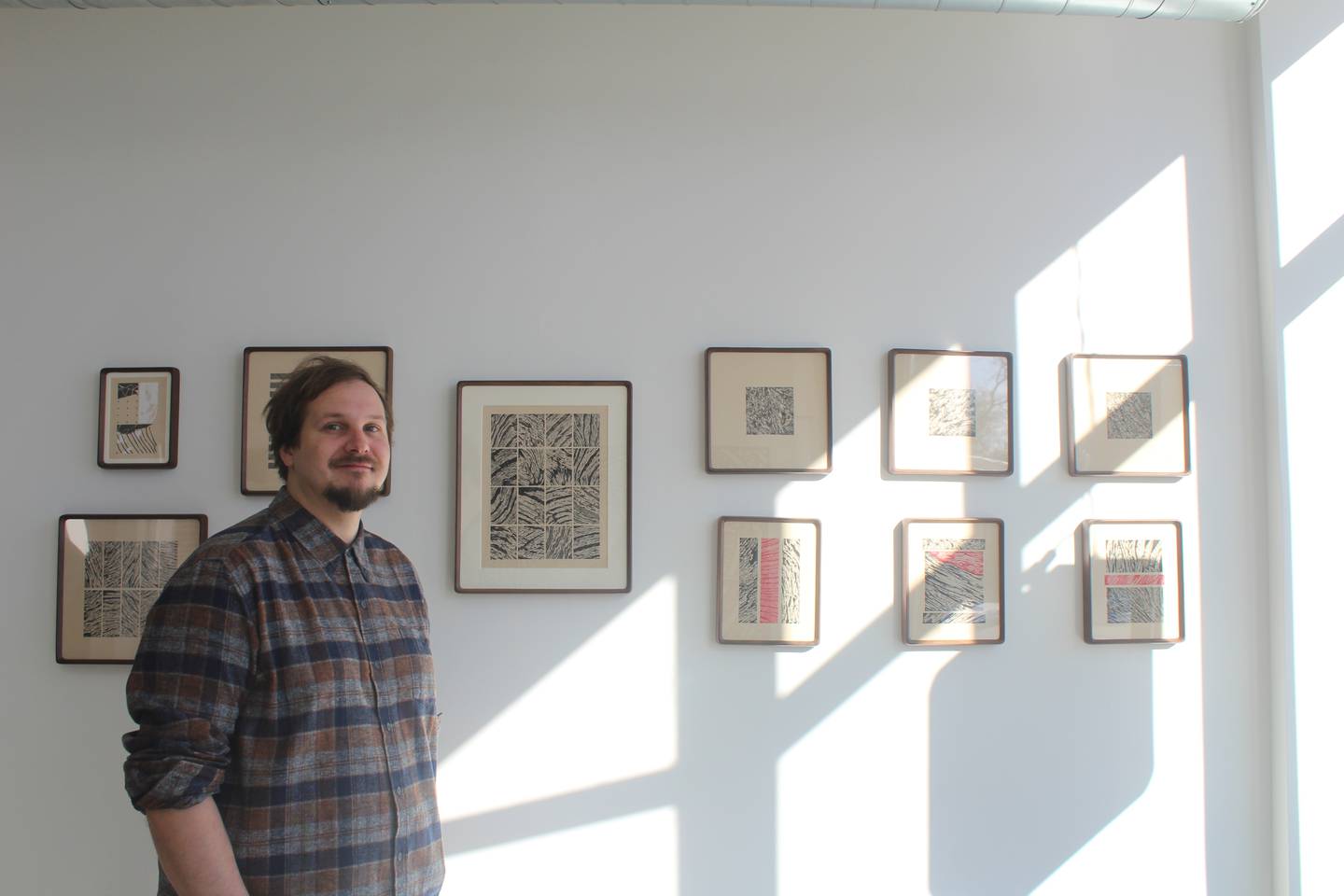 Local artist Ryan Tippery stands next to his illustrations on display at the All Ways art gallery in Fox River Grove.