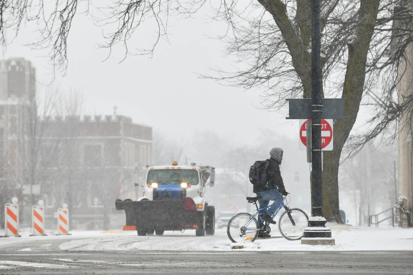 A snowplow travels along South Indiana Avenue as a bicyclist braves the wind Tuesday, Feb. 12, as snow arrived to the Kankakee area.