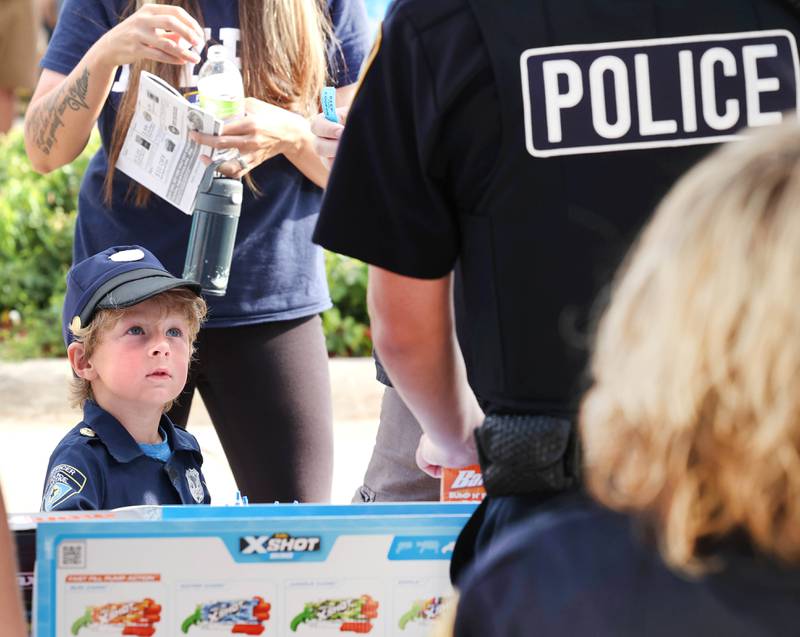 Vinny Berres dressed as a police officer meets the real thing at the Sycamore Police booth during National Night Out Tuesday, Aug. 1, 2023, in the Hy-Vee parking lot in Sycamore.