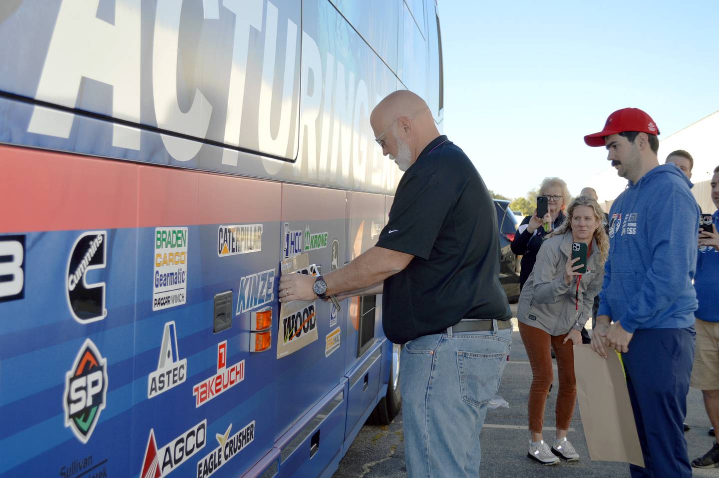 Joe Leddy, a quality engineer at Woods Equipment, prepares to put the Oregon-based company's decal sticker on the Association of Equipment Manufacturer's Manufacturing Express bus on Tuesday, Oct. 8, 2024. Woods was one of 80 stops across 20 states on AEM's Manufacturing Express tour.