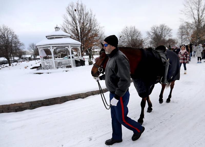 Ryan Bentele, from Operation Wild Horse,  leads Whiskey Tango Foxtrot, in the Riderless Horse ceremony in honor of POW/MIA veterans during McHenry's Wreath Laying Ceremony in honor of fallen veterans on Friday, Dec. 5, 2025,, at St. Mary's Catholic Cemetery in McHenry. The event was hosted by McHenry American Legion Post 491 and Team Home Depot.