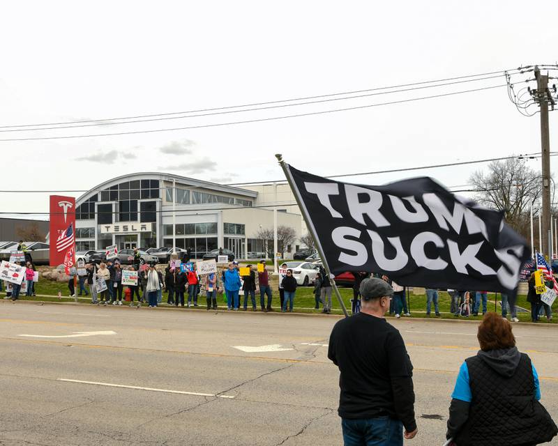 Community members line Ogden Ave. holding signs and flags near the Tesla dealership on Saturday April 5, 2025, in Lisle during the Hands Off Demonstration.