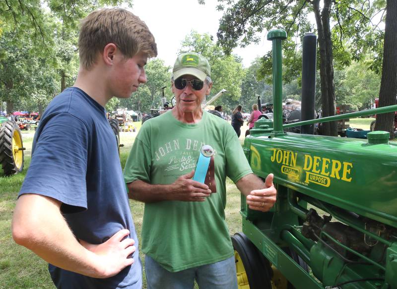 Dennis Shanks, (right) from Elburn, talks about his 1937 Model B John Deere tractor with his grandson Luke Golobitsh, 18, from Naperville, Thursday, Aug. 8, 2024, during the 67th annual Sycamore Steam Show and Threshing Bee at Taylor Marshall Farm.
