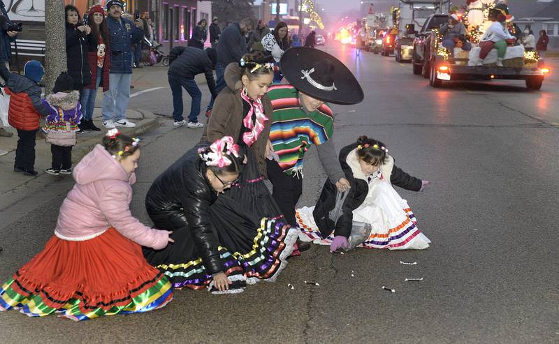 Children dressed in traditional Mexican clothing pick up some candy Saturday, Dec. 10, 2022, along the parade route during the Winter Parade in Oglesby.