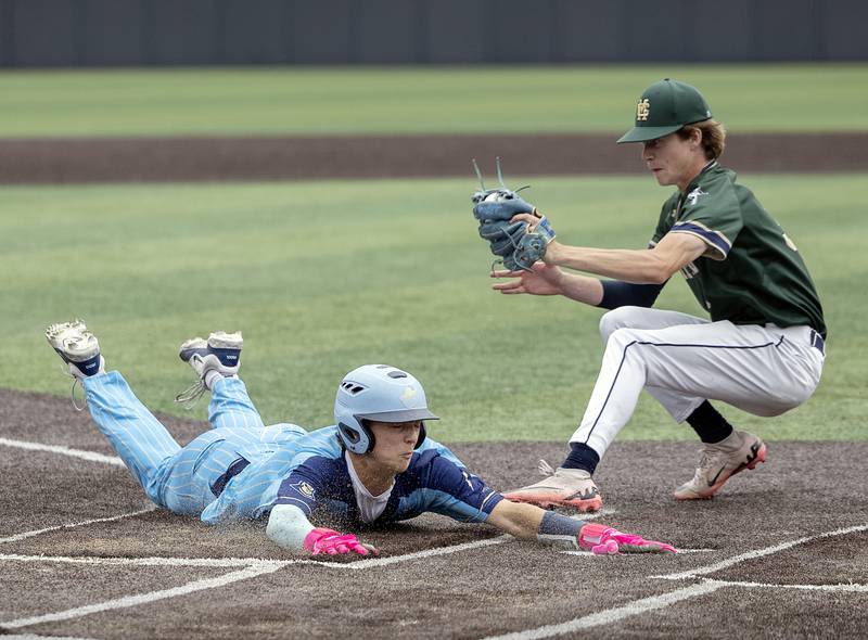 Ottawa Marquette’s Easton Debernardi steals home to tie up the game in the bottom of the seventh as Father McGivney’s Evan Koontz goes for the tag Saturday, June 7, 2025, during the Class 1A state baseball final at Illinois Field in Champaign.