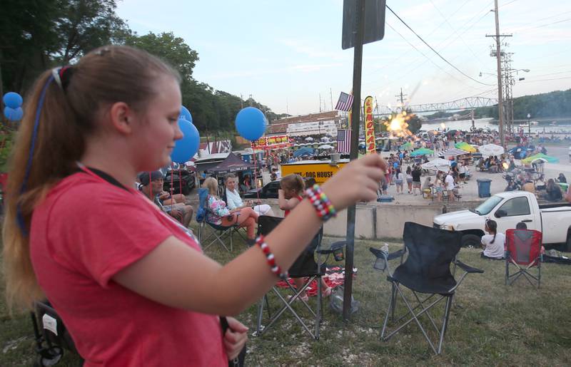 Olyvia Daner of La Salle lights a sparkler during the "Rock the River 4th of July celebration on Thursday, July 3, 2025 along Water Street in Peru.