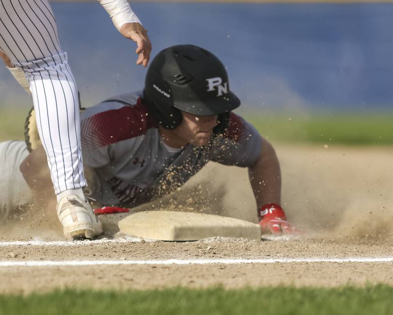 Plainfield North's Brendan Henderson (10) dives back to first during a pickoff attempt during baseball game between Plainfield North at Oswego East, Monday, April 28, 2025 in Oswego.