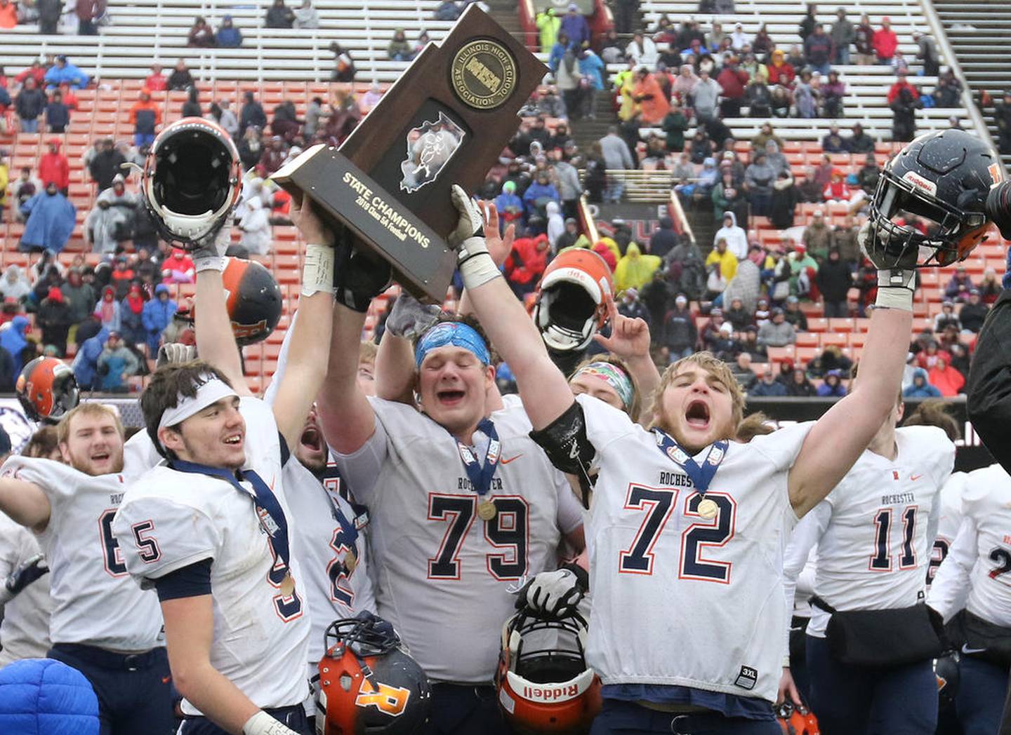 Rochester captains Clay Bruno, (left) Nathan Hoerner and Camden Ramsey (right) hoist the trophy after their Class 5A state football championship victory over St. Rita Saturday in Huskie Stadium at Northern Illinois University.