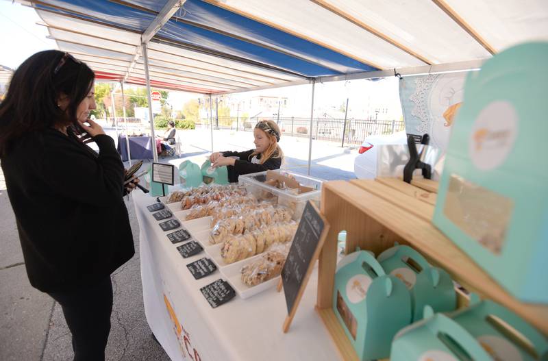 Patty Cavanagh of Glen Ellyn buys cookies with the help of Claira Kratz of Plainfield  during the last day of the Glen Ellyn French Market Sunday, Oct. 20, 2024.