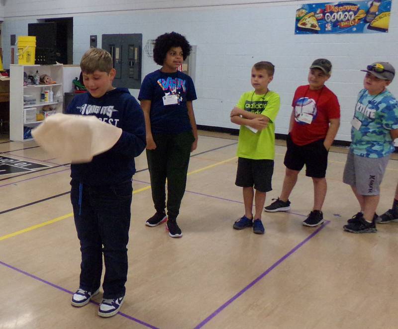 An Illinois junior chef student gets ready to toss a practice pizza dough Wednesday, June 22, 2022, at Northlawn School in Streator during a program led by the University of Illinois Extension.