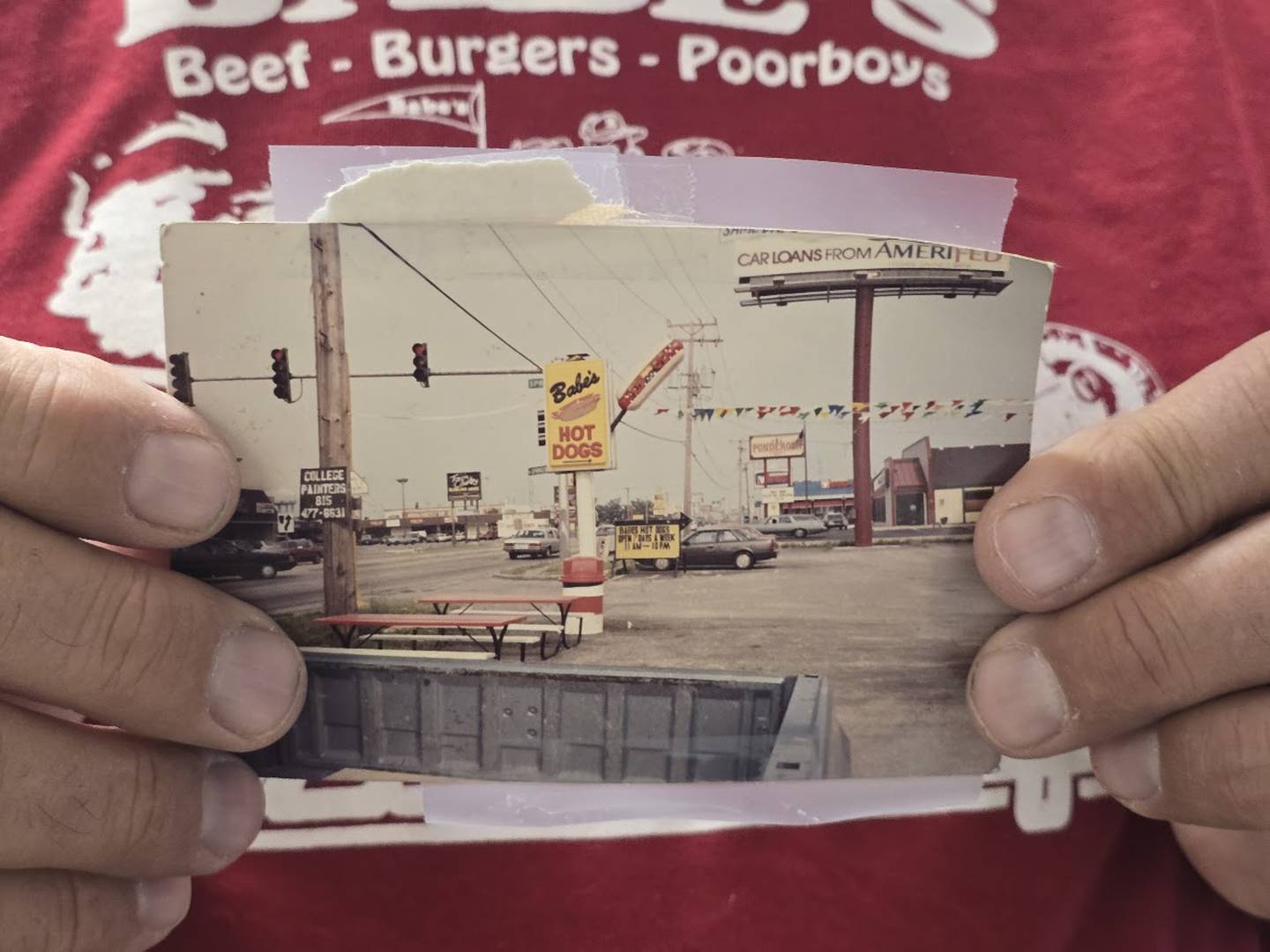 Tim Reilly, owner of Babe's Hot Dogs in Joliet, holds a photo of his restaurant's first sign on Tuesday, Dec. 9, 2025. Reilly has listed his business, which many consider a staple in the community, for sale.