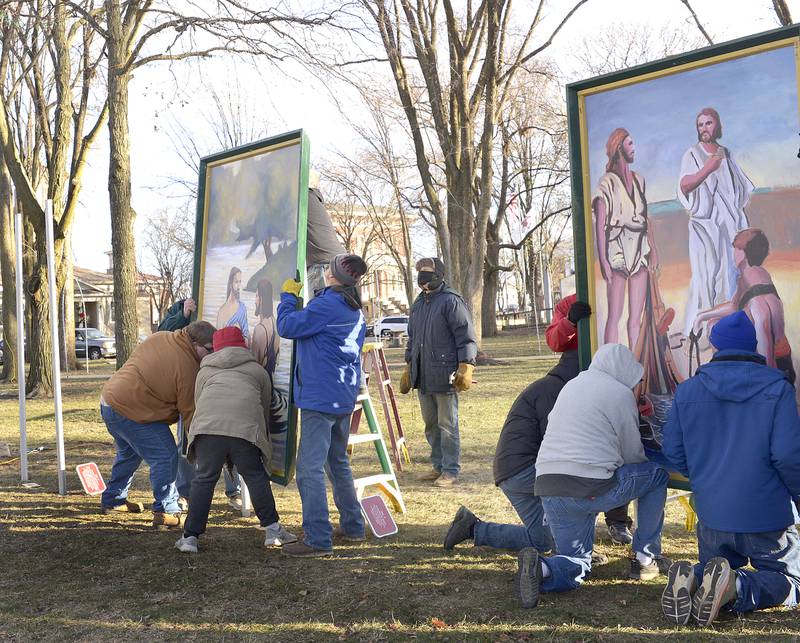 Volunteers lift to install 2 of the 16 paintings depicting the life of Christ Saturday in Ottawa’s Washington Square.The 4-foot by 7-foot paintings. The Ottawa Freedom Association has erected the paintings each year since 1992 after winning a lengthy court battle.