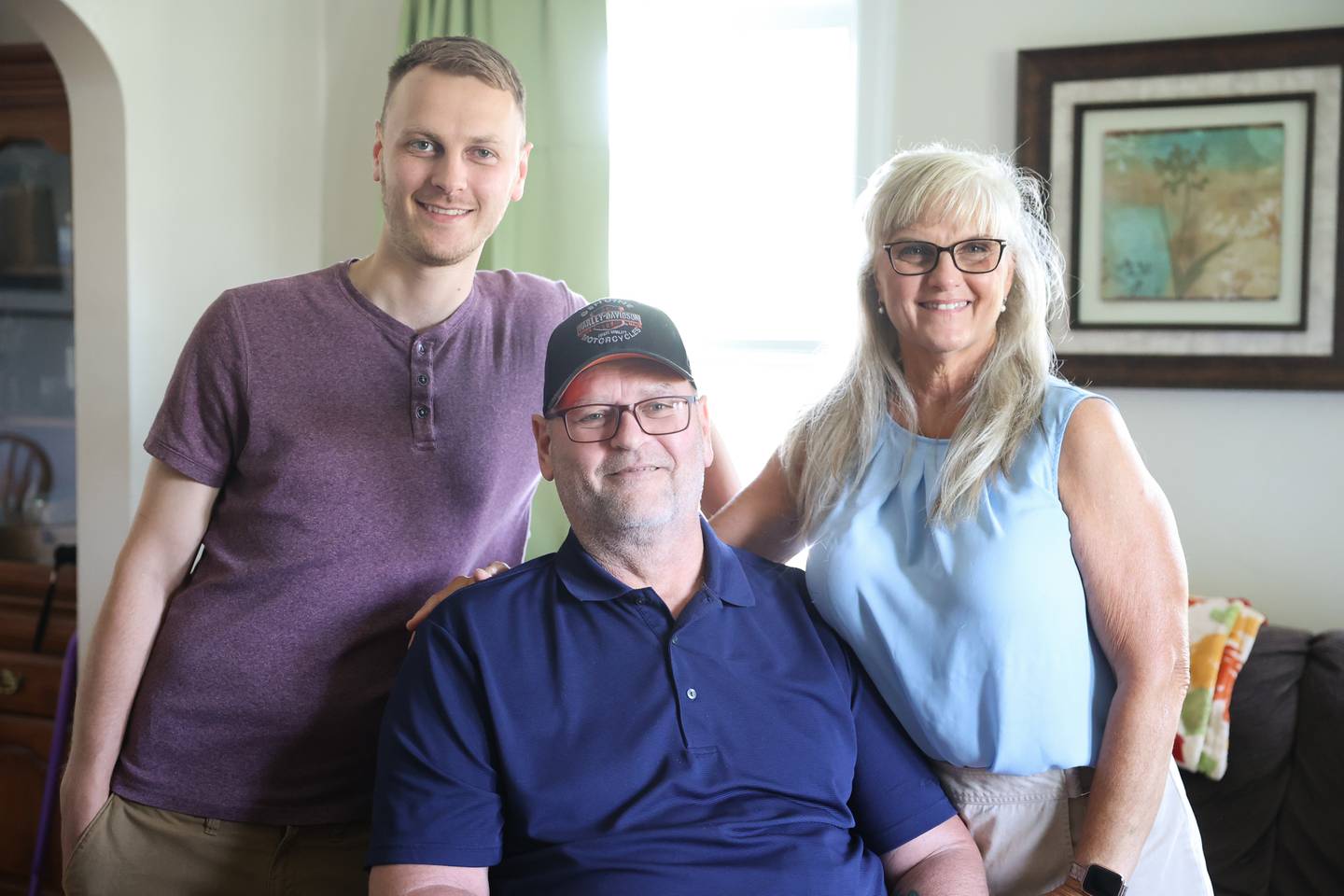 Sean Flannery, left, stands with his father and mother, Tim and Joann. Nearly a year after Tim’s motorcycle accident that left him in critical condition, Tim is still recovering with the help of his son and wife. Wednesday, June 15, 2022 in Joliet.