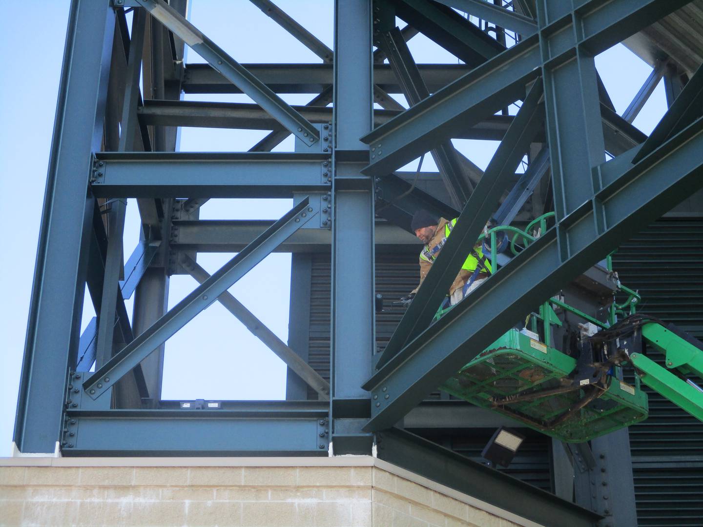 A painter on a crane works on one of the towers at the entrance to Slammers Stadium in Joliet on Friday. April 11, 2025