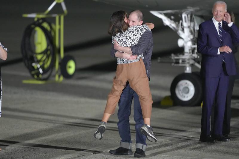Reporter Evan Gershkovich hugs his mother, Ella Milman, as President Joe Biden, right, looks on at Andrews Air Force Base, Md., following their release as part of a 24-person prisoner swap between Russia and the United States, Thursday, Aug. 1, 2024. (AP Photo/Manuel Balce Ceneta)