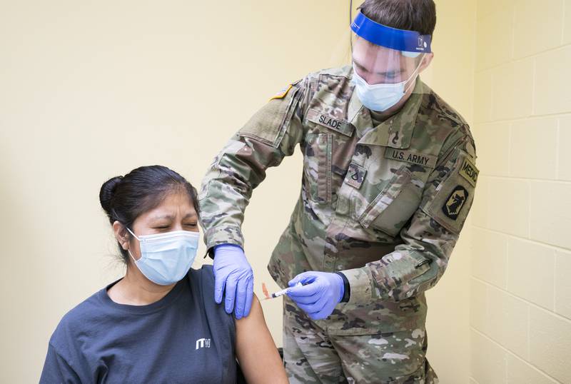 Employee Margarita Del La Cruz reacts as she receives a dose of Johnson & Johnson COVID-19 vaccine from Pfc. Matthew Slade of the Illinois National Guard, during a vaccination clinic in March at ITW Medical in Hebron hosted by the Illinois National Guard and the McHenry County Department of Health. The clinic was open to workers at the manufacturing plant.  Ryan Rayburn for Shaw Media