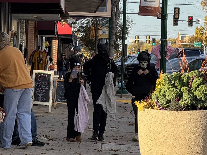 A SWAT team officer, Batman and the Punisher walk down Liberty Street in Morris Thursday for Downtown Trick or Treat. Photo taken on Thursday, Oct. 30, 2025.