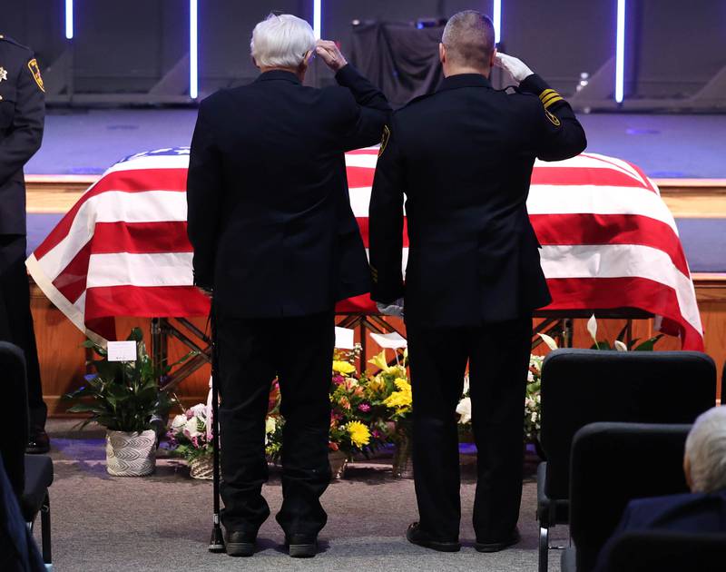Former DeKalb County Sheriff Wilbur Scott, (left) and current DeKalb County Sheriff Andy Sullivan salute the casket of Roger Scott, former sheriff and younger brother of Wilbur, during visitation Thursday, March 6, 2025, at Bethany Road Bible Church in DeKalb. Roger Scott, who was the county sheriff for more than 30 years, died on Feb. 23 at the age of 78.