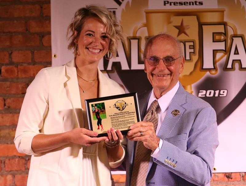 Tori (Bunzell) Kueker smiles while holding her award with Lanny Slevin Emcee, during the Shaw Media Illinois Valley Sports Hall of Fame on Thursday, June 8, 2023 at the Auditorium Ballroom in La Salle.