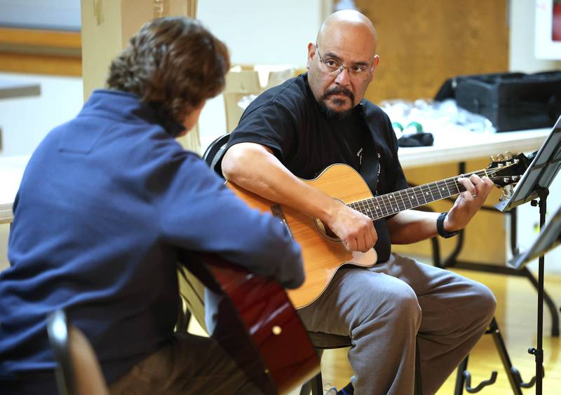 Veterans Ron Lofton (left) gives Manuel Olalde some tips on playing guitar Tuesday, Nov. 26, 2024 during the Kishwaukee Special Recreation Association’s Chords and Camaraderie at the Hopkins Park Community Center in DeKalb.