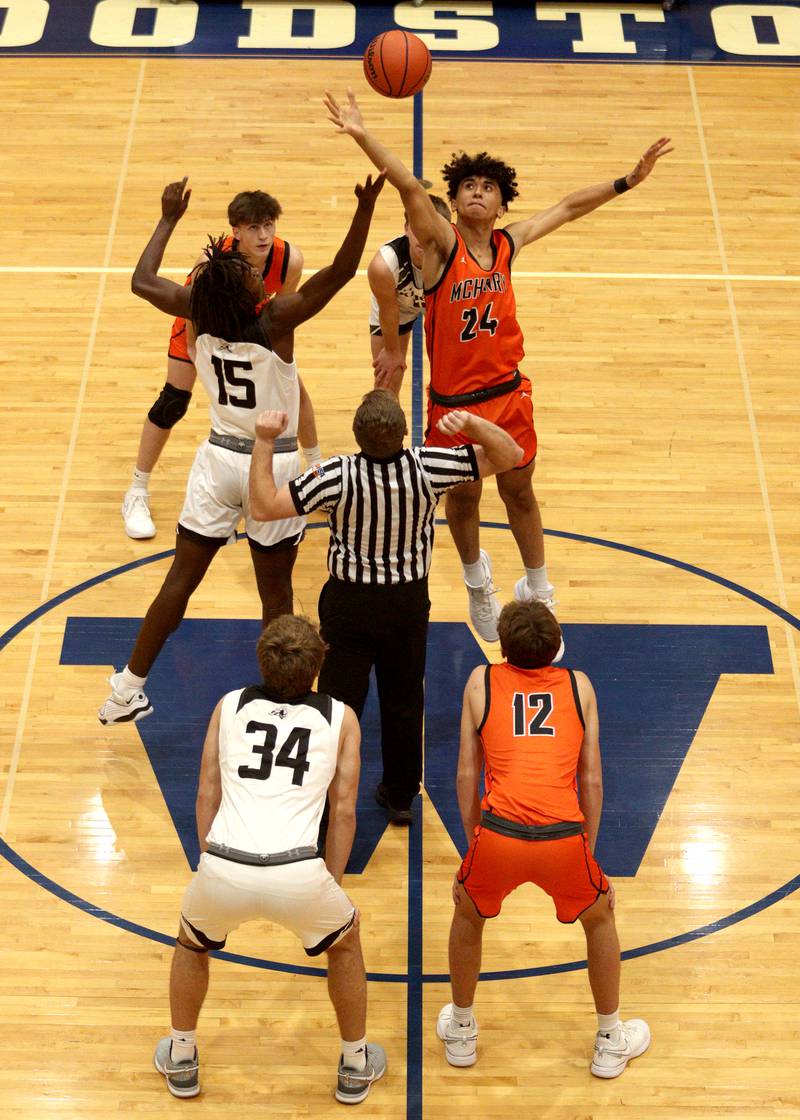 McHenry’s Adam Anwar and Kaneland’s Evan Ross tip off to begin the championship game in Hoops for Healing basketball tournament action at Woodstock Wednesday.