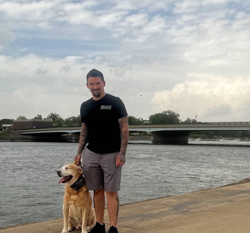 Dog trainer and owner of DK9services, Dylan Blackburn, stands with rescue dog, Copper, along the riverfront in Dixon, Illinois. Blackburn works suicide prevention group, 22Mohawks, to train and pair companion dogs with veterans and first responders.