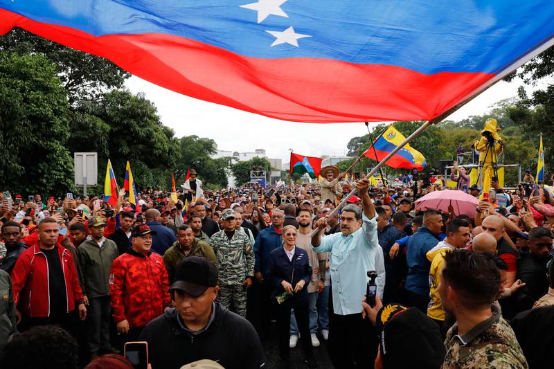 President Nicolas Maduro waves a flag during a rally marking the anniversary of the Battle of Santa Ines, which took place during Venezuela's 19th-century Federal War, in Caracas, Venezuela, Wednesday, Dec. 10, 2025. (AP Photo/Cristian Hernandez)