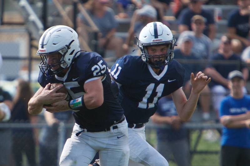 Cary-Grove's Peyton Seaburg hands the ball off to Colin Desmet for a gain against McHenry on Saturday, Sept. 17,2022 in Cary.