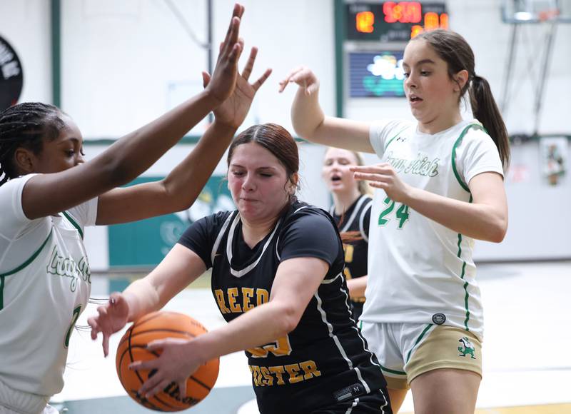 Reed-Custer's Brooklyn Gonzalez tries to secure a rebound under pressure from Bishop McNamara's Anna Manes, right, and Mahlyia Johnson during Bishop McNamara's 60-36 victory over Reed-Custer in the IHSA Class 2A Bishop McNamara Regional semifinals on Monday, Feb. 16, 2026.