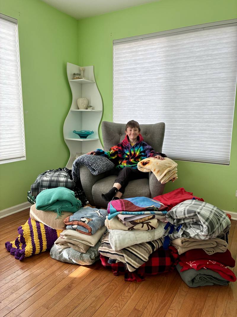 Aaden Barcus, 9, of Crystal Lake, sits surrounded by about 25 blankets he collected to give to people who are unhoused.