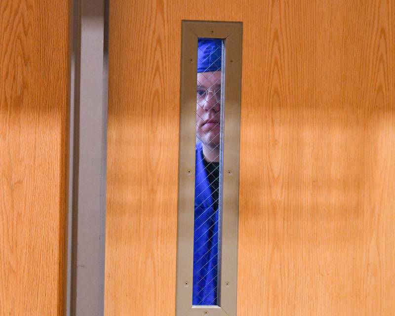 Dakota Allen looks through the gym door windows from the hallway before the start of the Class of 2024 graduation held on Saturday, May 18, 2024, at Genoa-Kingston High School, 980 Park Ave., Genoa.